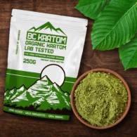 Green BC Kratom Bag laying on a wooden table next to a bowl of Green Kapuas Kratom Powder