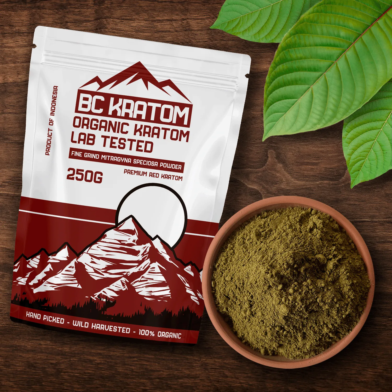 BC Kratom Red 250g Bag set on a wooden table with a bowl of Red Bali Kratom Powder and red vein kratom leaves