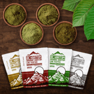 4x 250g BC Kratom bags laying on a wooden table beside four different bowls of kratom powder.