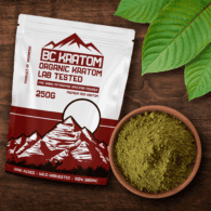 Red BC Kratom Bag laying on a wooden table next to a bowl of Red Maeng Da Kratom Powder