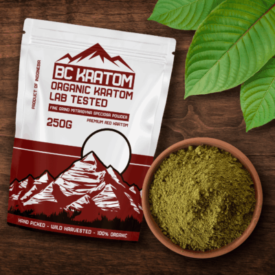 Red BC Kratom Bag laying on a wooden table next to a bowl of Red Maeng Da Kratom Powder