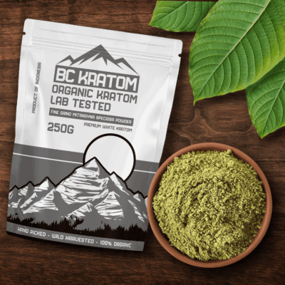 White BC Kratom bag laying on a wooden table beside a bowl of Super White Kratom Powder