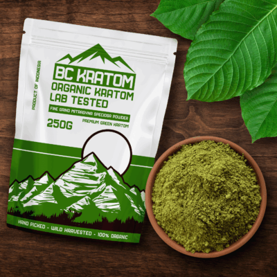 Green BC Kratom Bag laying on a wooden table next to a bowl of Super Blend Kratom Powder