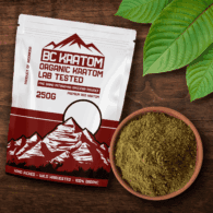 Red BC Kratom Bag laid flat on a wooden table with a bowl of Red Jongkong Kratom powder