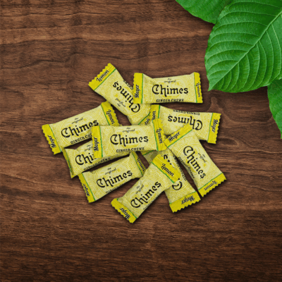 Original Meyer Lemon Ginger Chimes candies loosely laid down on a wooden table with leaves.