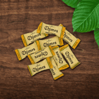 Pile of Original Mango Ginger Chimes candies loosely laid down on a wooden table with leaves.