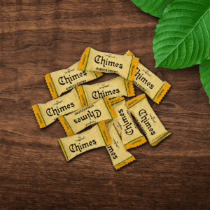 Pile of Original Mango Ginger Chimes candies loosely laid down on a wooden table with leaves.