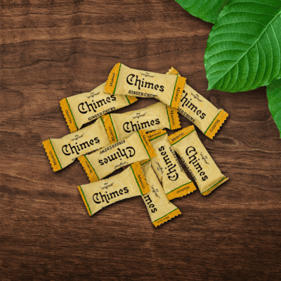 Pile of Original Mango Ginger Chimes candies loosely laid down on a wooden table with leaves.
